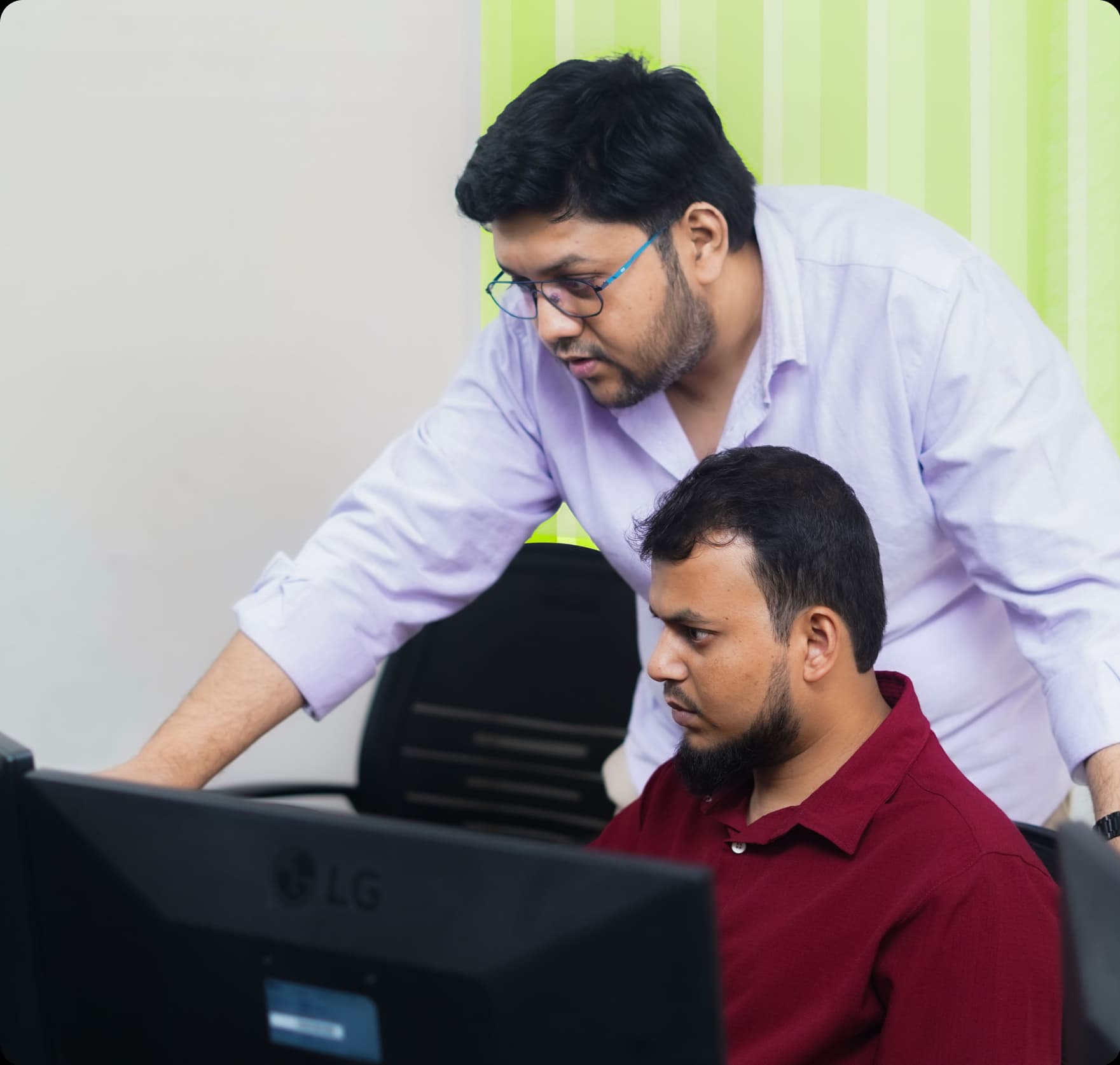 Two engineers reviewing data dashboards on a monitor, collaborating on AI automation and business intelligence work.
