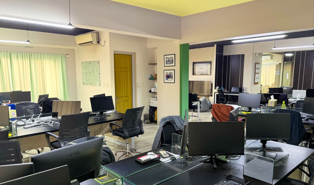 An open office workspace with rows of computer workstations.