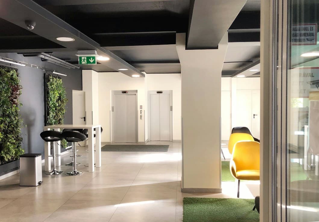 Bright office lobby with a green wall and bar stools