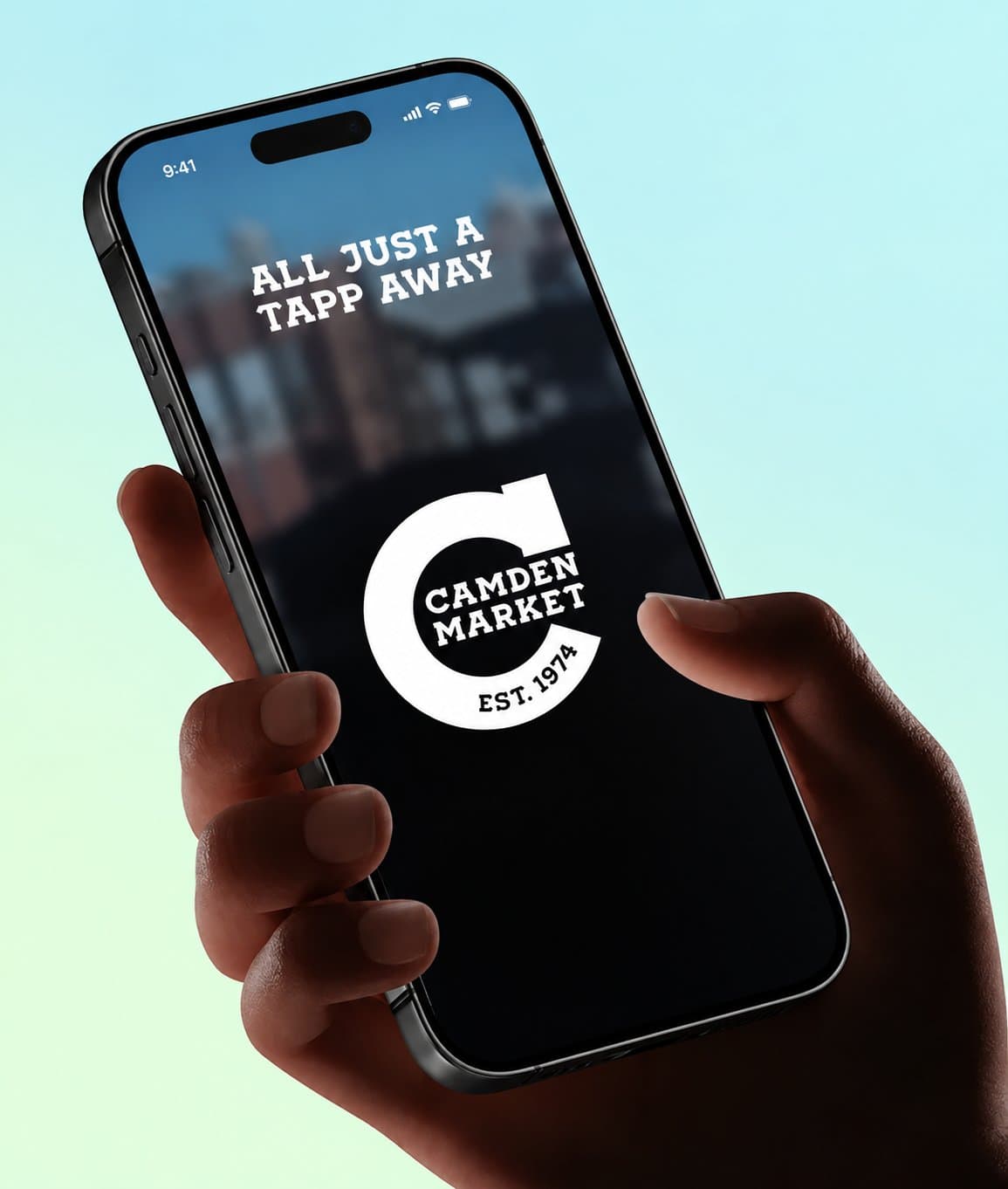 Hand holding a phone showing the Camden Market app splash screen with the 'All just a tapp away' tagline and the Camden Market Est. 1974 logo, on a mint-to-cyan gradient background