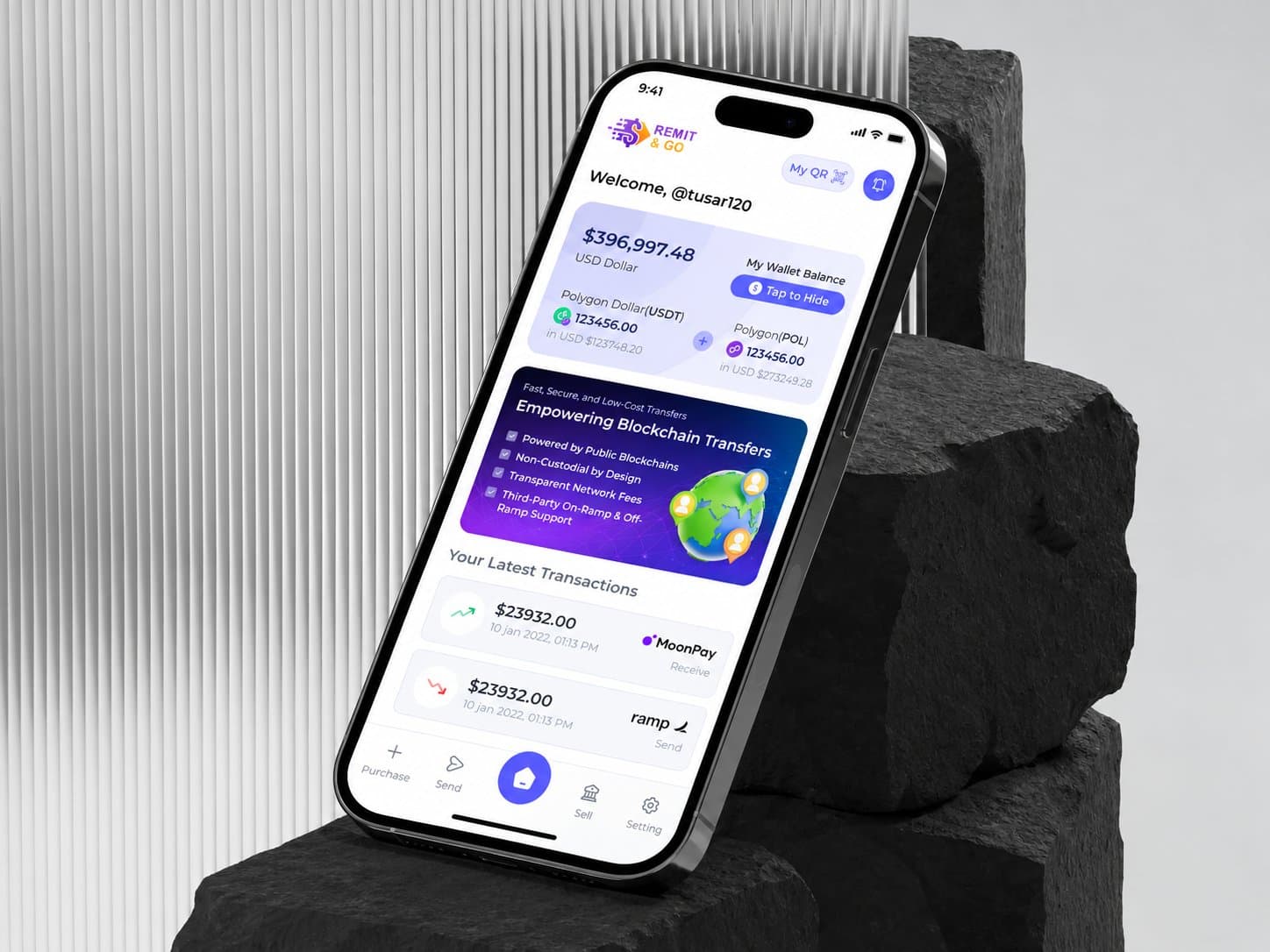 Smartphone showing the Remit&Go wallet home screen with balance, blockchain transfer banner and latest transactions, leaning against dark stone in front of a ribbed glass panel