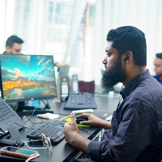 A software engineer working at a desk with multiple screens