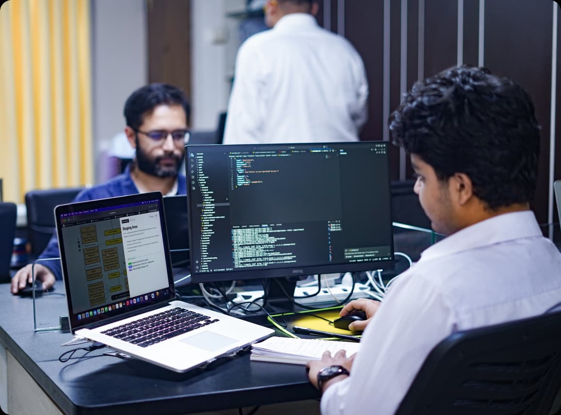Engineers at a desk with code on screen